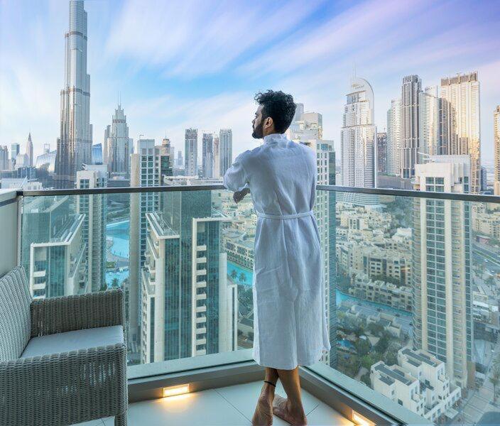 迪拜Ramble Stay Hostel Burj Khalifa view的站在一个城市的阳台上的人
