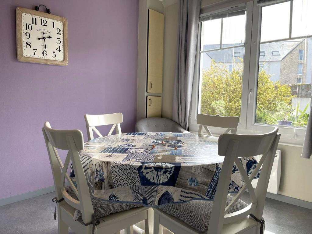 佩罗斯-吉雷克Maison Perros-Guirec, 3 pièces, 4 personnes - FR-1-368-218的餐桌、椅子和墙上的时钟