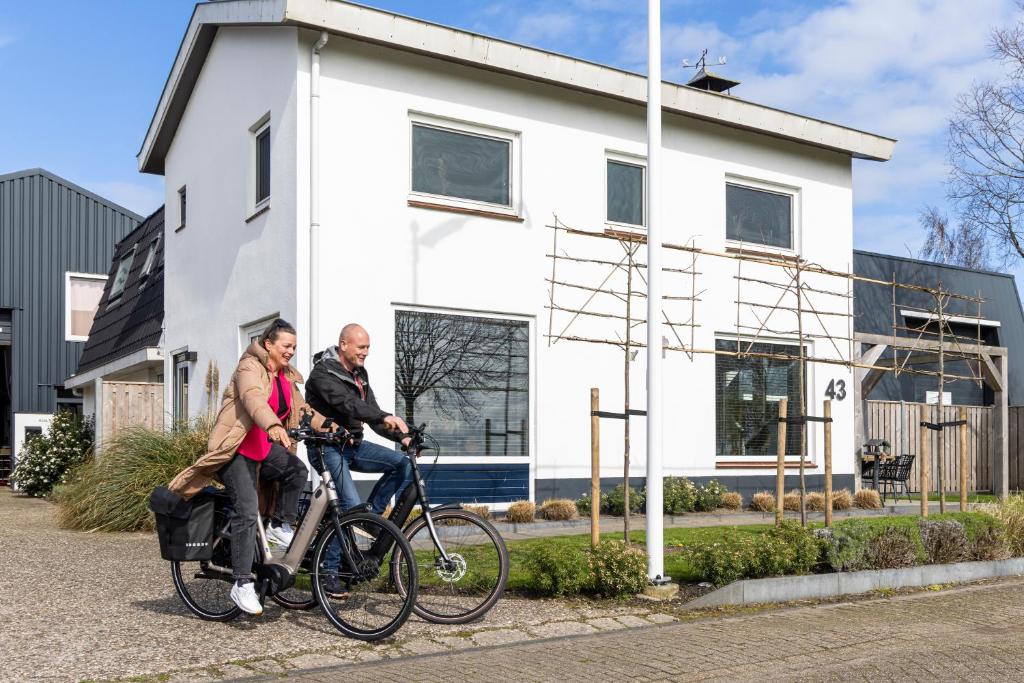 KolderwoldeWeeruusz的一名男子和一名女子骑着自行车在房子前