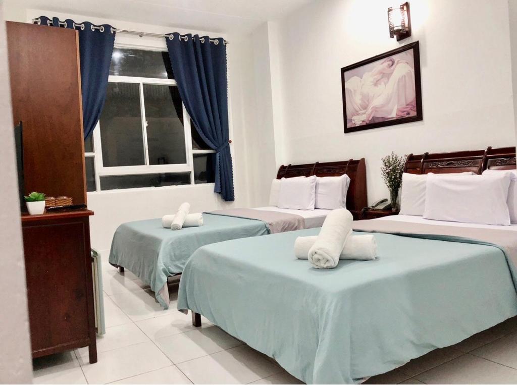 胡志明市Saigon Cozy2 Hotel的一间卧室设有三张床和窗户。