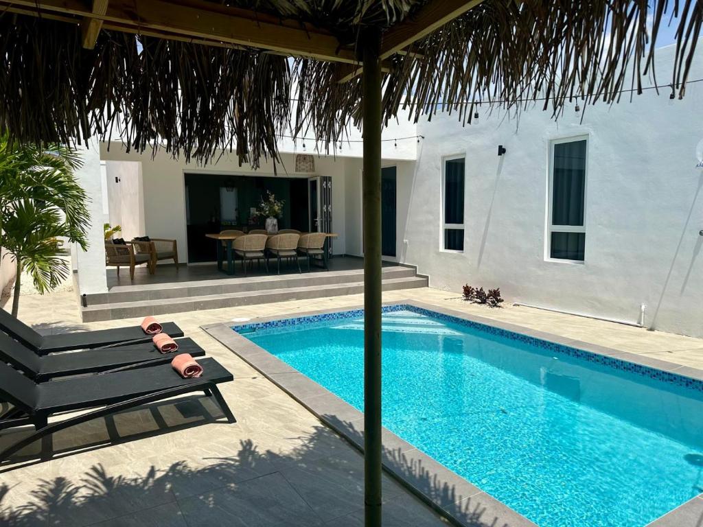 威廉斯塔德Villa Sol A Luna - Mambo Beach的房屋旁带椅子的游泳池