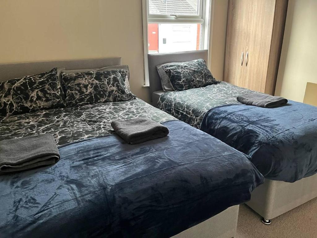 利物浦Lovely 2-Bed House in Liverpool的一间卧室配有两张带蓝色棉被的床