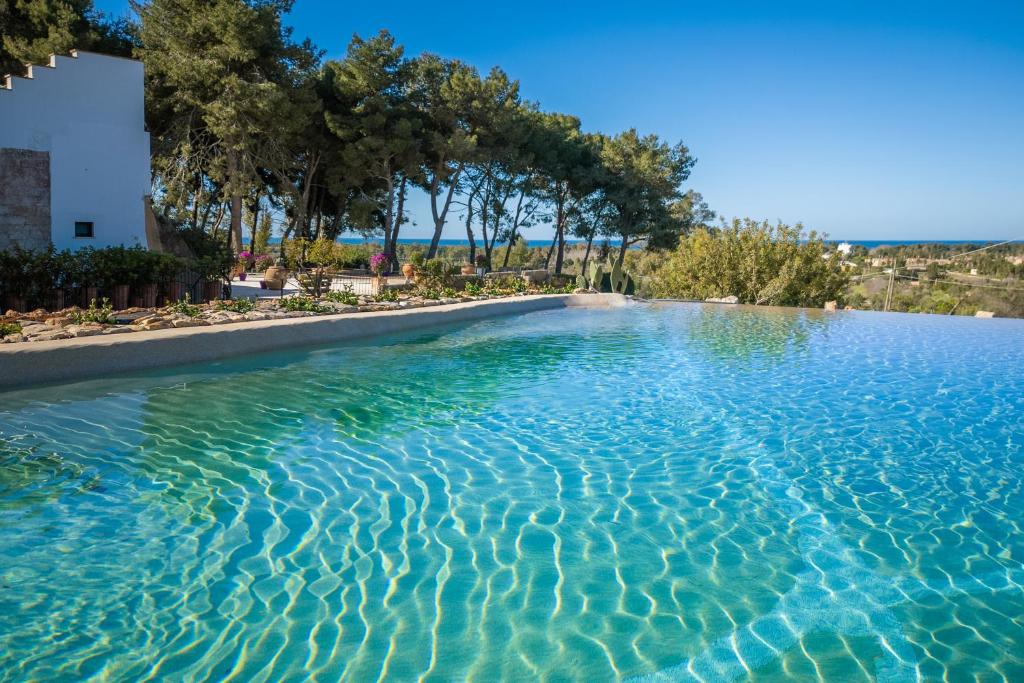 乌真托Hotel Masseria Fontanelle的拥有蓝色海水和树木的游泳池