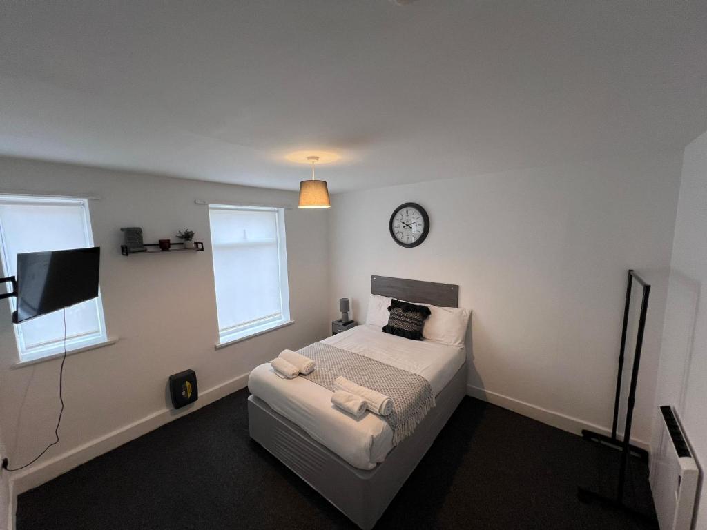 斯凯格内斯Harbour Flats的卧室配有一张床,墙上挂着一个钟