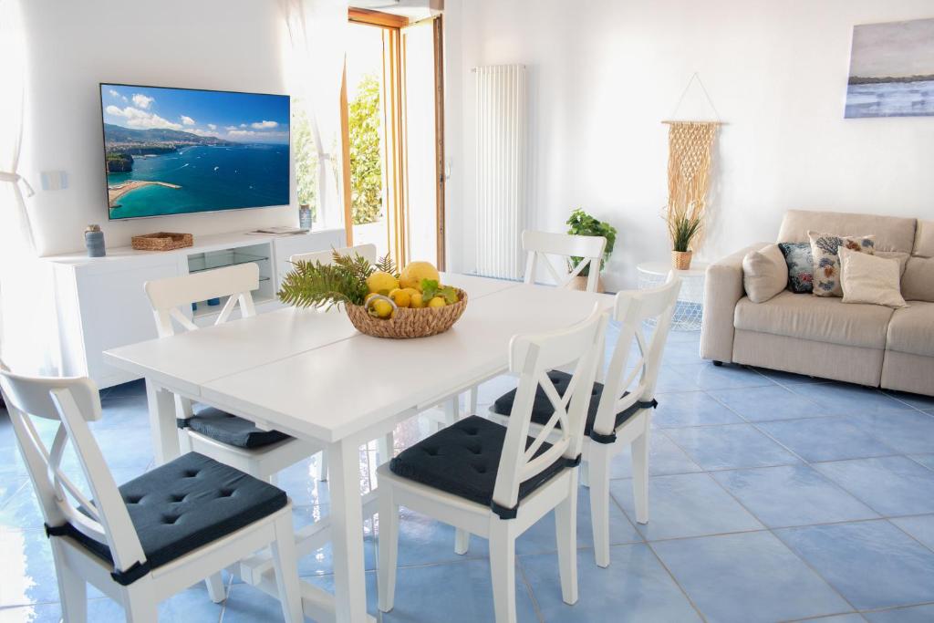 圣安吉洛Fountain House Sorrento的白色的饭厅桌子和椅子,还有一碗水果