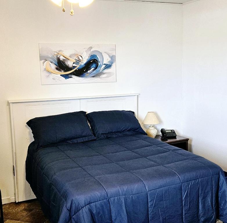 里穆斯基Motel Au Soleil couchant的卧室配有蓝色的床和墙上的绘画作品