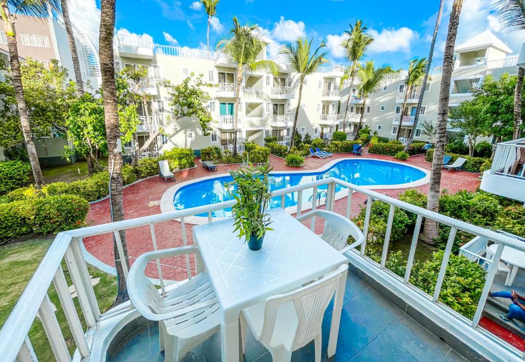 蓬塔卡纳BAVARO Los Corales SOL Caribe STUDIOS Rooms DELUXE WiFi Parking BEACH CLUB & SPA的一个带桌椅的阳台和一个游泳池