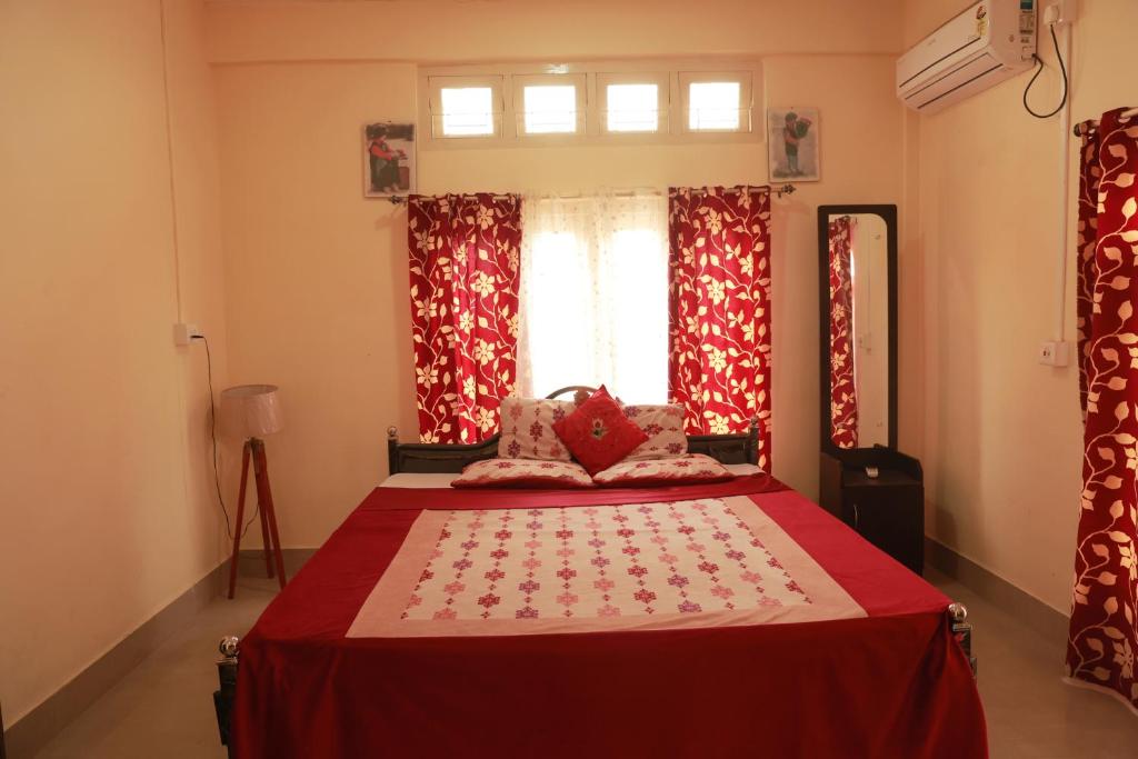 焦尔哈德Cozy Haven的一间卧室配有一张带红色窗帘的床和一扇窗户