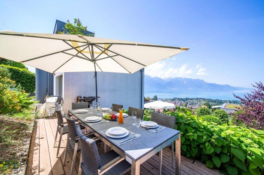 Le Châtelard-MontreuxPanoramic 3BD Dream Family Villa in Montreux by GuestLee的庭院内一张带遮阳伞的餐桌
