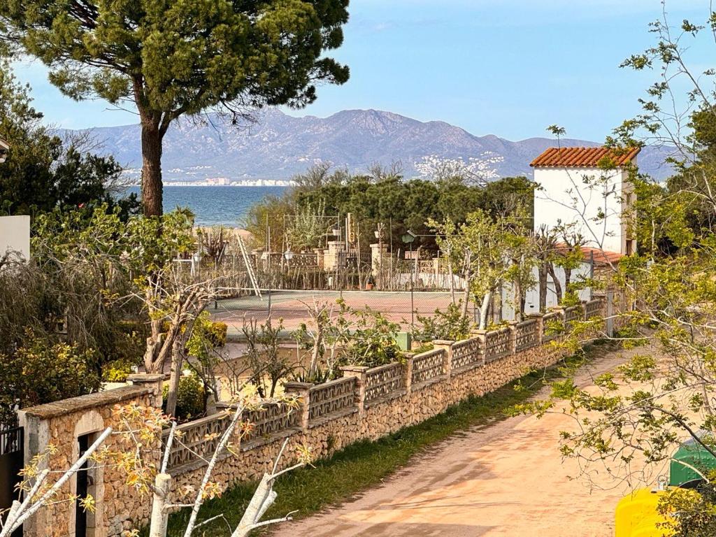 圣马蒂登普里斯Villa Mercè Empúries的一座花园,花园内有石墙,还有一棵树和一棵水