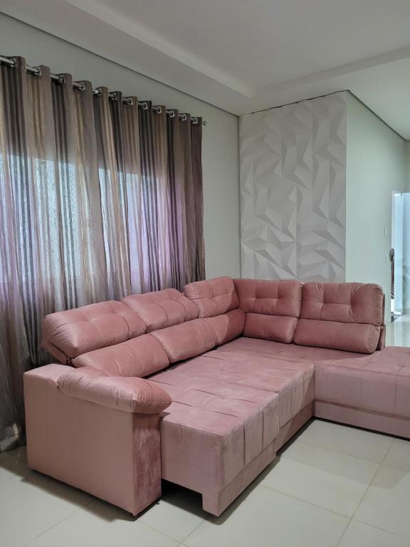 吉巴拉那Casa agradável com área gourmet的客厅配有带窗帘的粉红色沙发