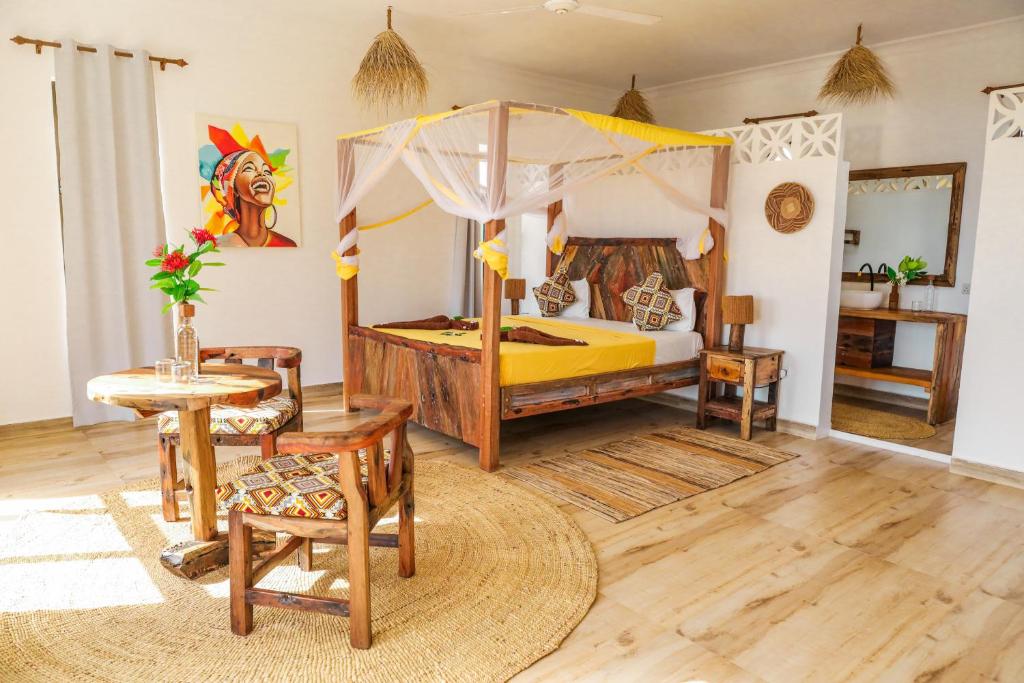 吉汶瓦Z-Lodge Zanzibar的一间卧室配有天蓬床和桌椅