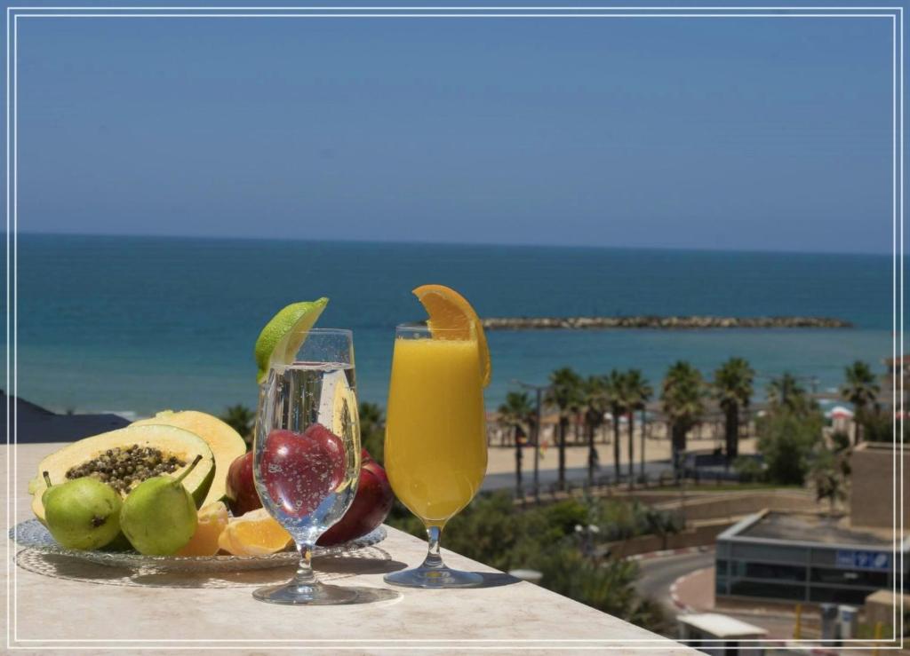 特拉维夫Bugrashov Beach 88 Hotel And Spa的海滩附近的桌子上放着水果和饮料托盘
