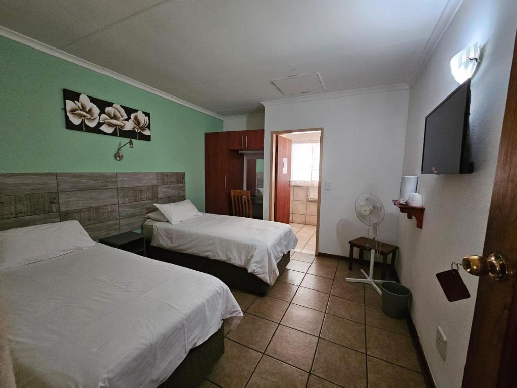 勒斯滕堡Rustenburg Palm Lodge的酒店客房设有两张床和一台平面电视。