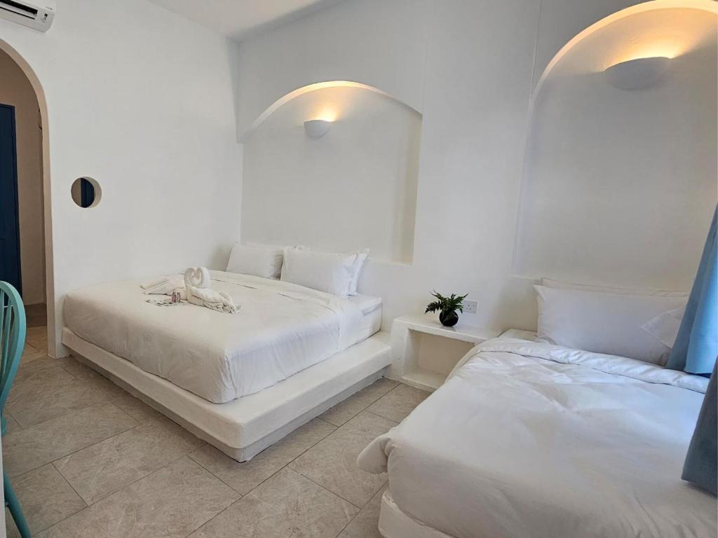 怡保Ipoh Santorini Hideaway - Hotel Inspired的一间白色卧室,配有两张床和镜子