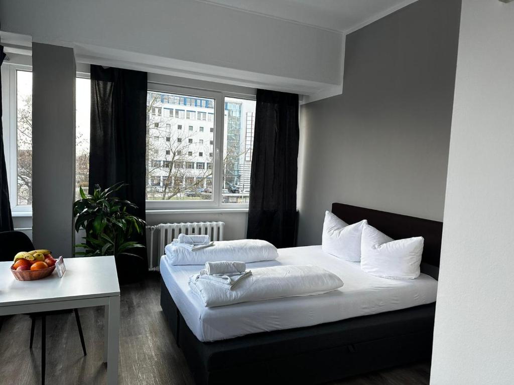 柏林Ootel.com的一间卧室设有两张床、一张桌子和窗户。