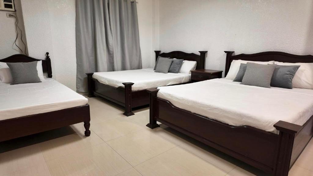 公主港CECILIAS INN的带3张白色床单的床的房间