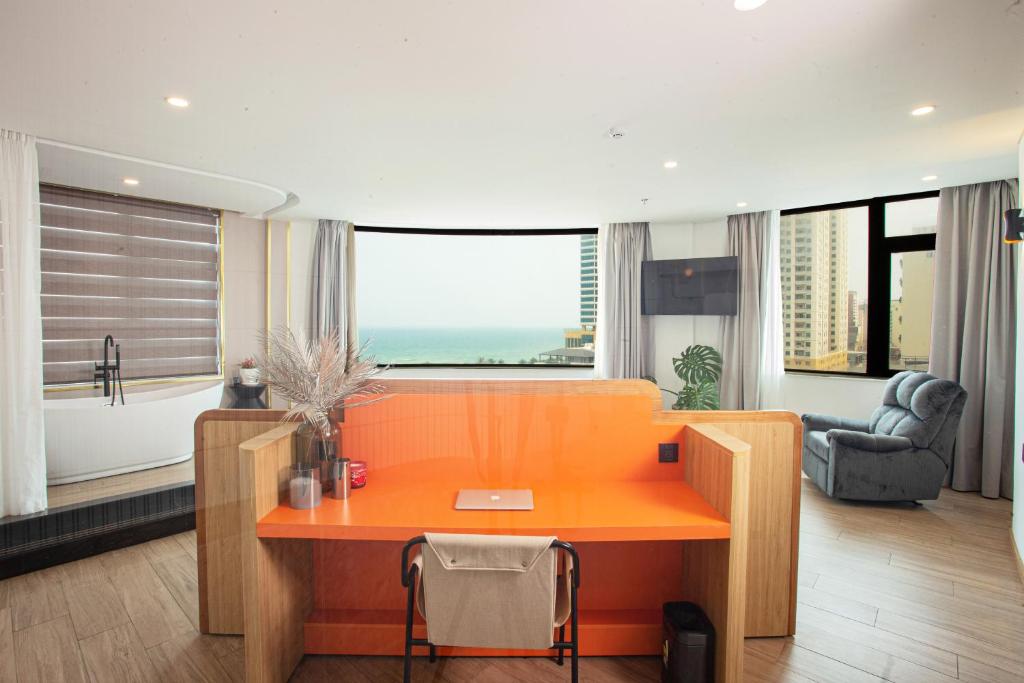 岘港PĀMA Boutique Hotel & Bistro的一张橙色的桌子,位于一个设有大窗户的房间