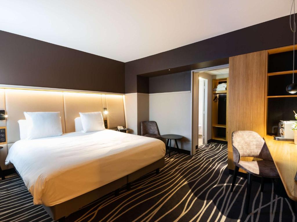 科尔马科尔马中心安特林登美居酒店的酒店客房设有一张大床和一张书桌。