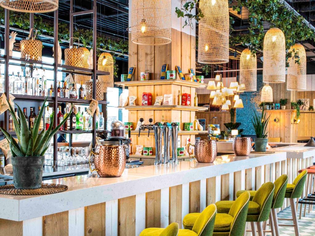 奥利Mercure Paris Orly Airport的餐厅设有1间带绿色椅子的酒吧