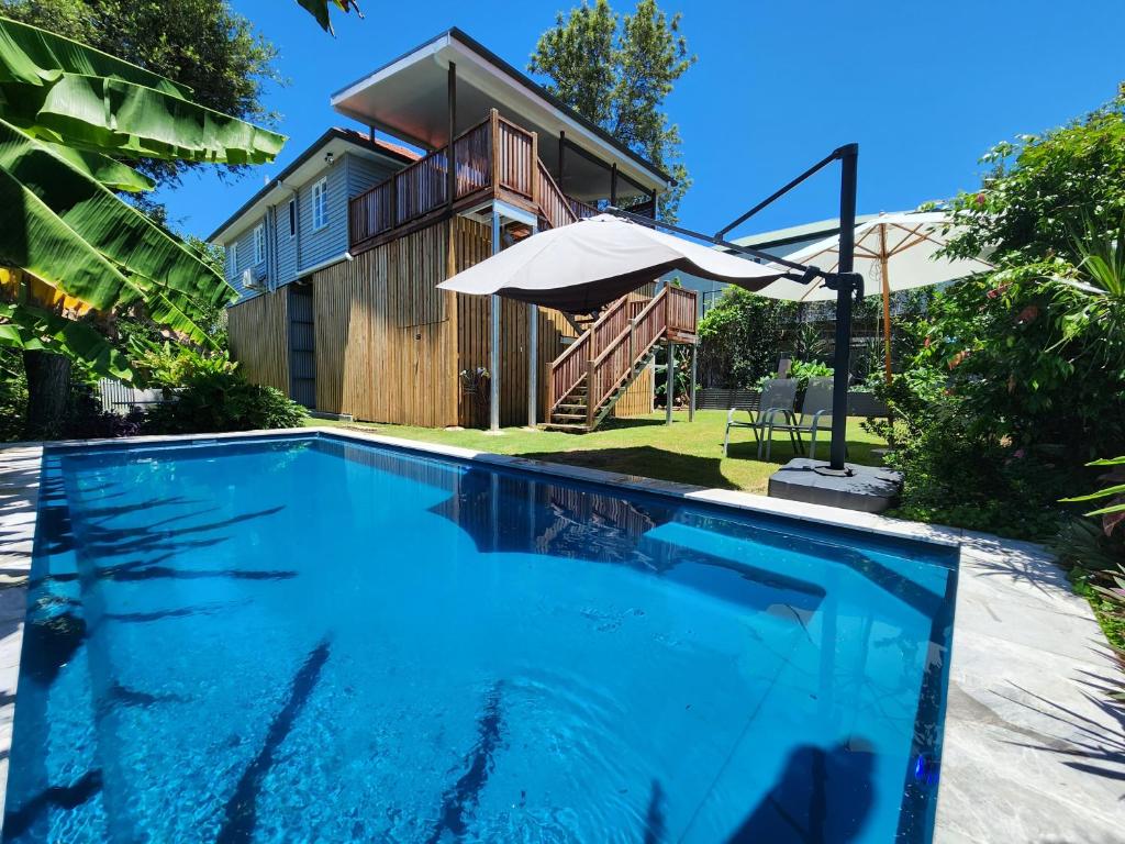 布里斯班OXLEY Private Heated Mineral Pool & Private Home的一座带遮阳伞的房屋前的游泳池