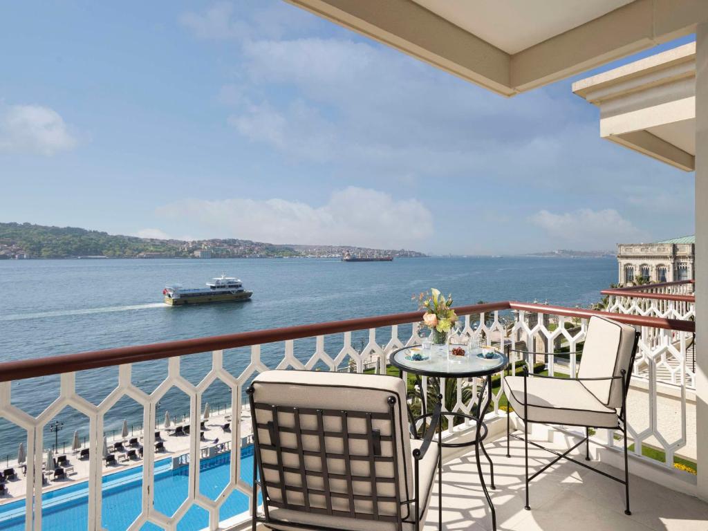 伊斯坦布尔伊斯坦布尔塞拉宫凯宾斯基酒店的阳台配有桌椅,俯瞰着水域
