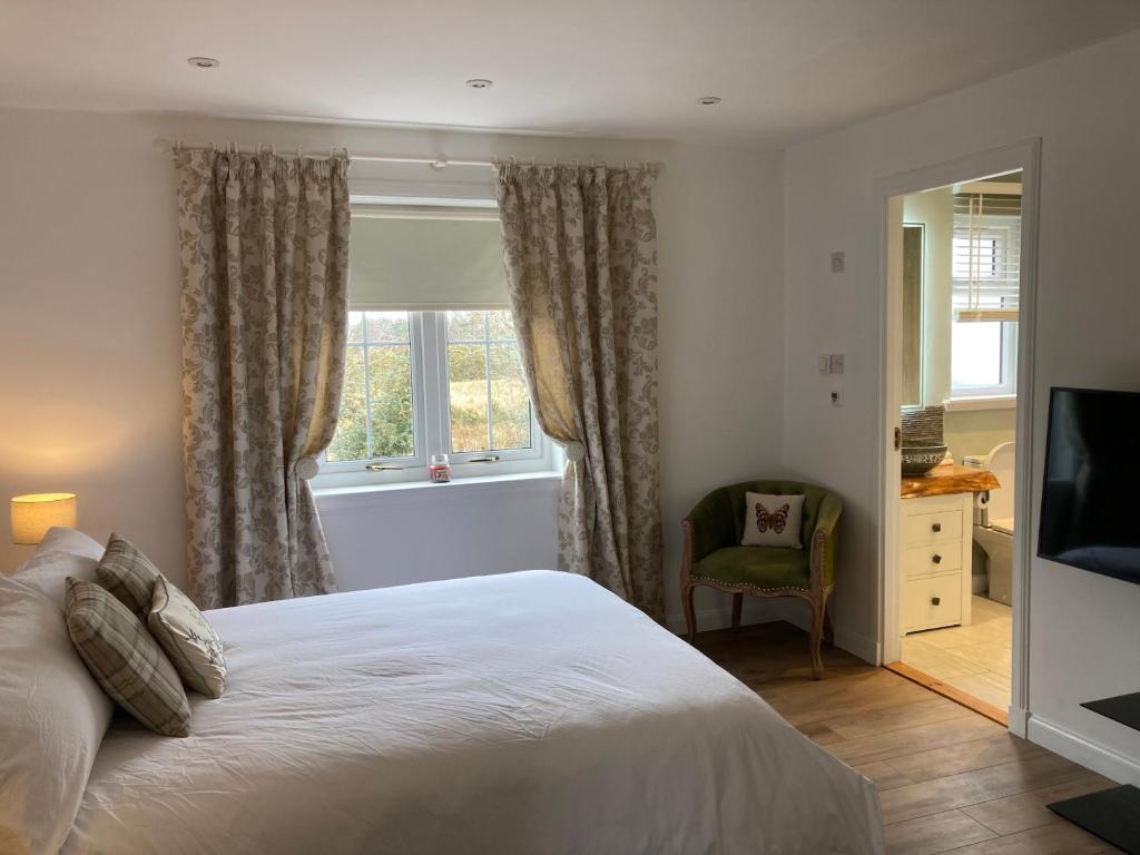 多诺赫Clashmore Wood的一间卧室设有一张床、一个窗口和一把椅子