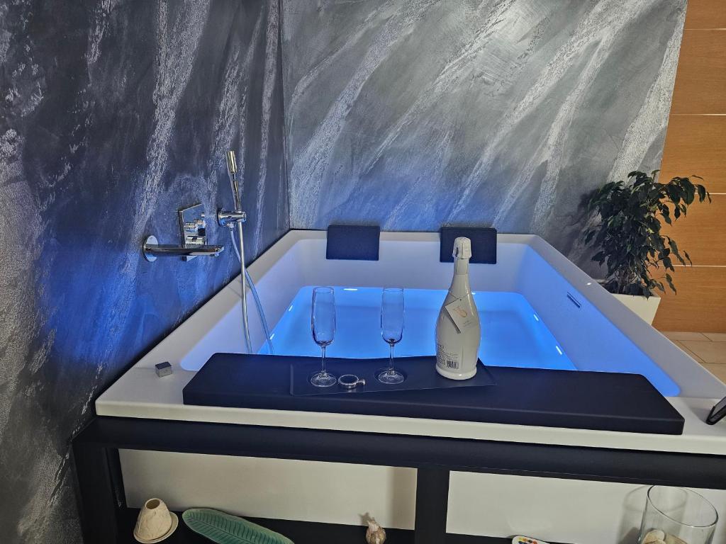 圣埃拉莫因科莱Blue Hole Jacuzzi Suite e B&B Santeramo in Colle的浴缸配有一瓶葡萄酒和两杯酒