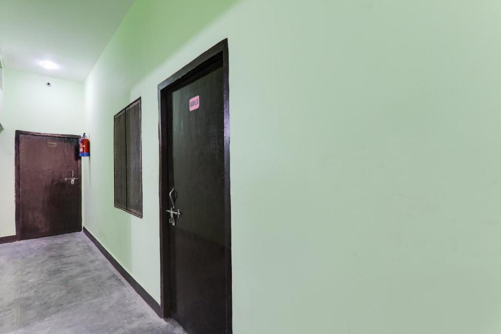 勒克瑙Relax Inn Hotel的走廊上设有两个黑色的门,地板上