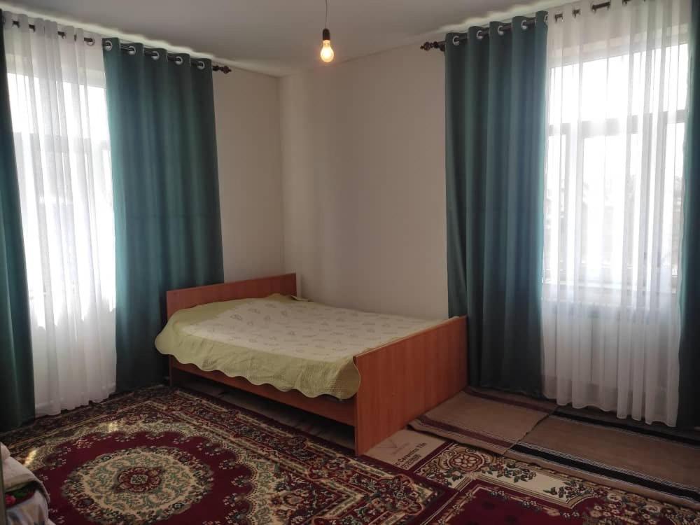 卡拉科尔Emir Guest House in Karakol的一间卧室配有床和两个带窗帘的窗户