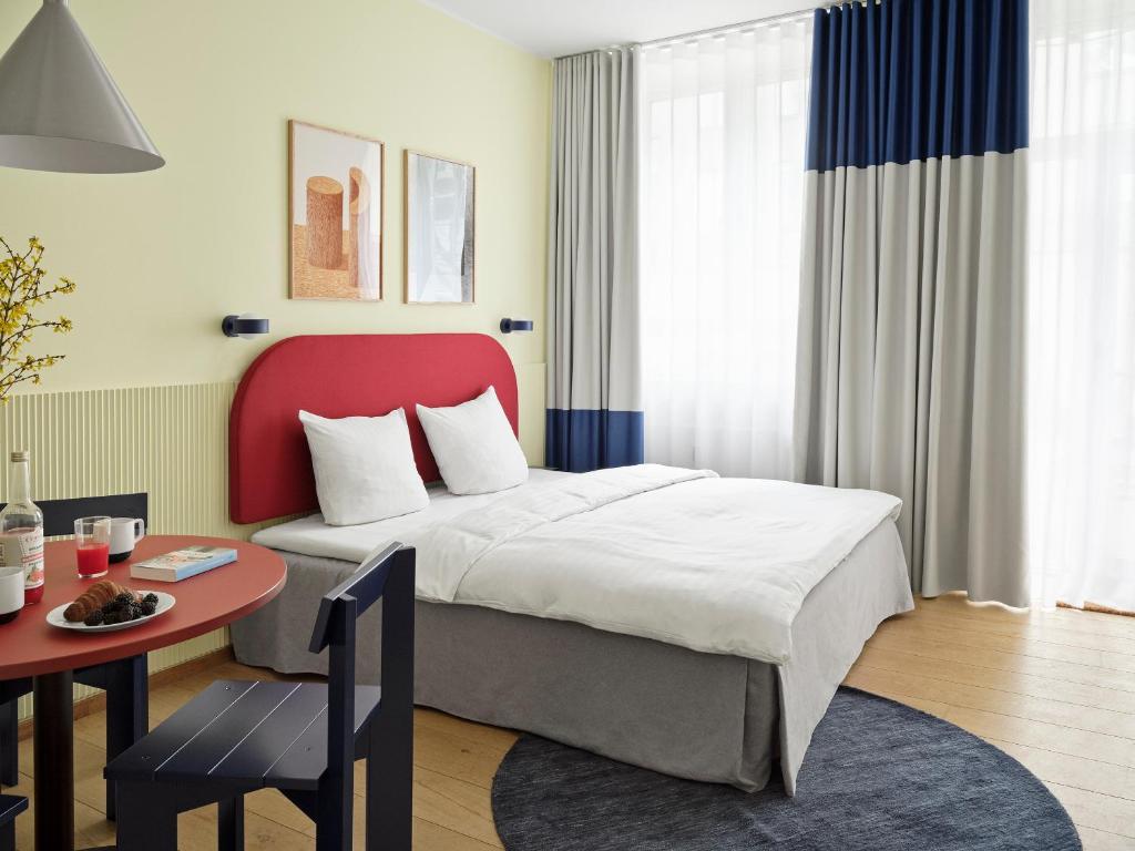 哥本哈根BRIK Apartment Hotel的一间卧室配有一张带红色床头板的床和一张桌子