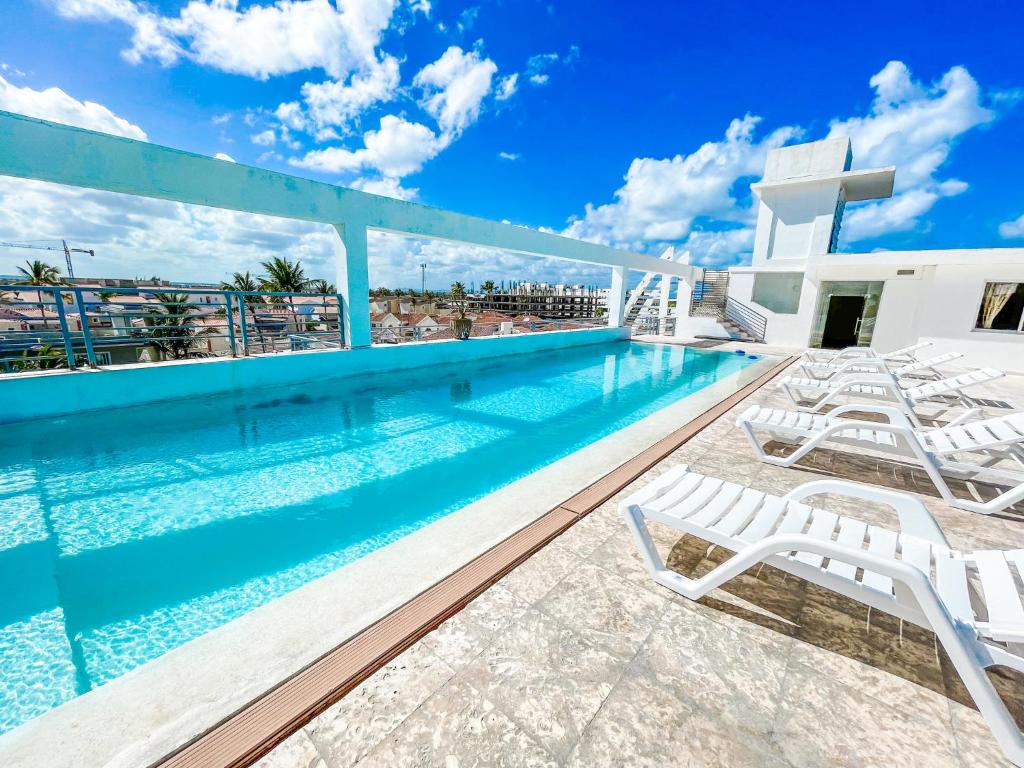 蓬塔卡纳DUKASSI SUITES Hotel ROOMS BEACH Bavaro WIFI Parking ROOFTOP POOL & SPA的一座带躺椅的游泳池位于大楼旁