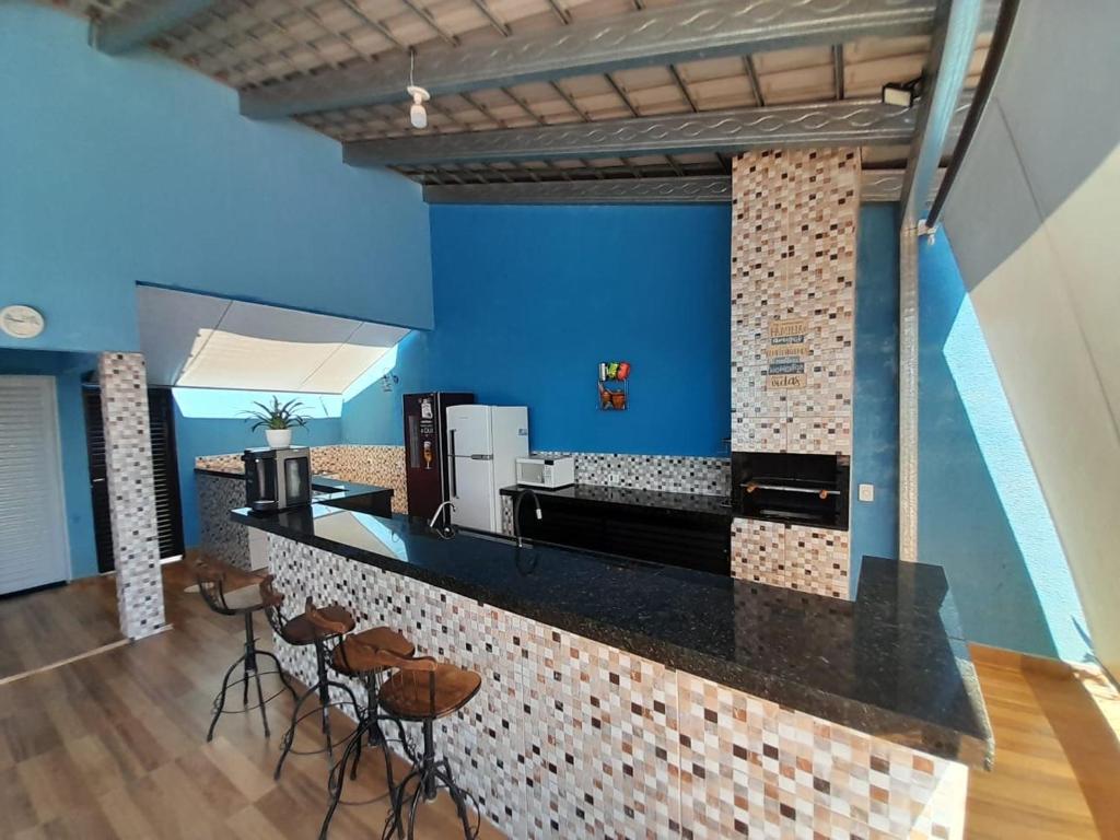 里贝朗普雷托Espaço céu Azul的厨房设有蓝色的墙壁和带凳子的台面。
