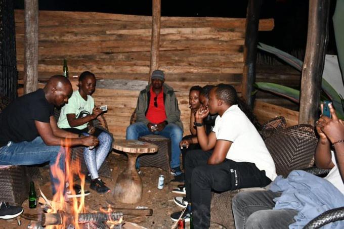RwumbaIWACU ECO LODGE的一群人围坐在火炉旁
