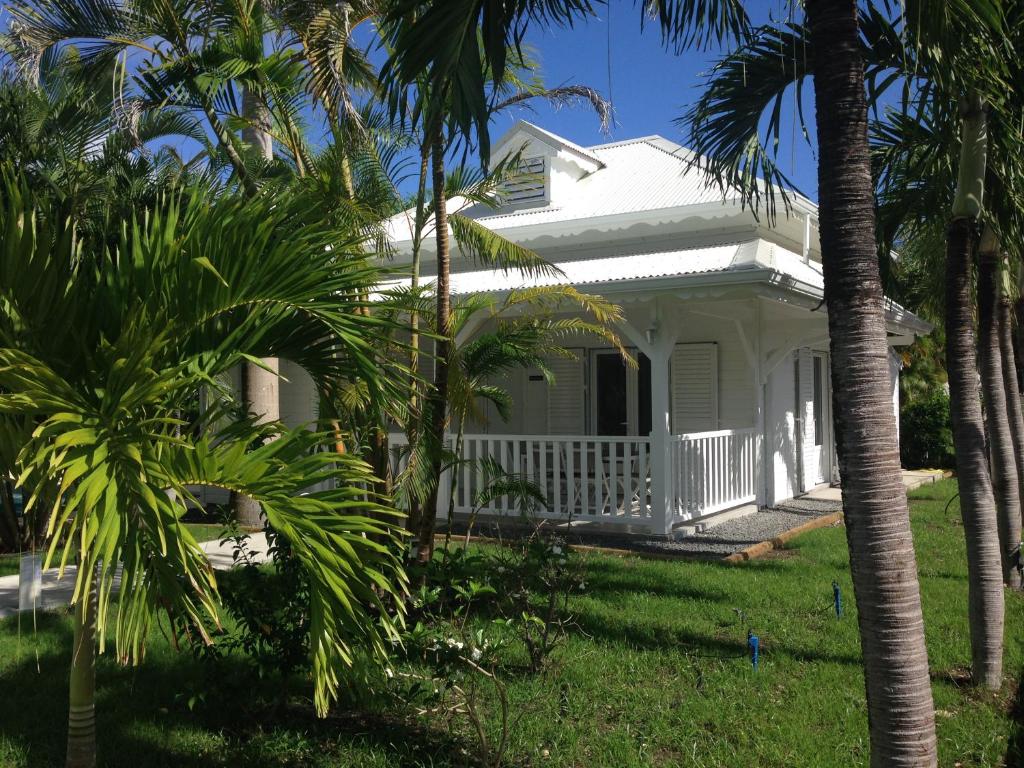 圣弗朗索瓦Chambres d'hôtes et villas chez Flo的院子里有棕榈树的白色房子