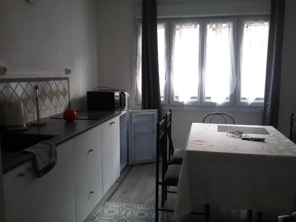 博韦Appart'hôtel的厨房配有桌子、两扇窗户和桌椅