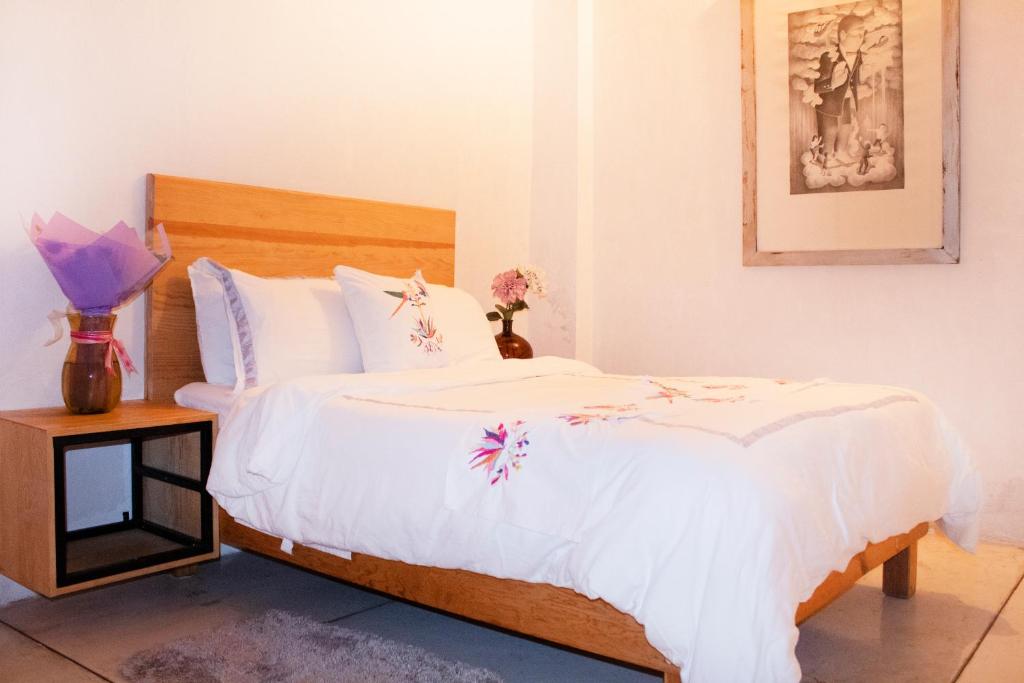 瓦哈卡市Hospedaje Donaji的一间卧室配有白色床单和鲜花。