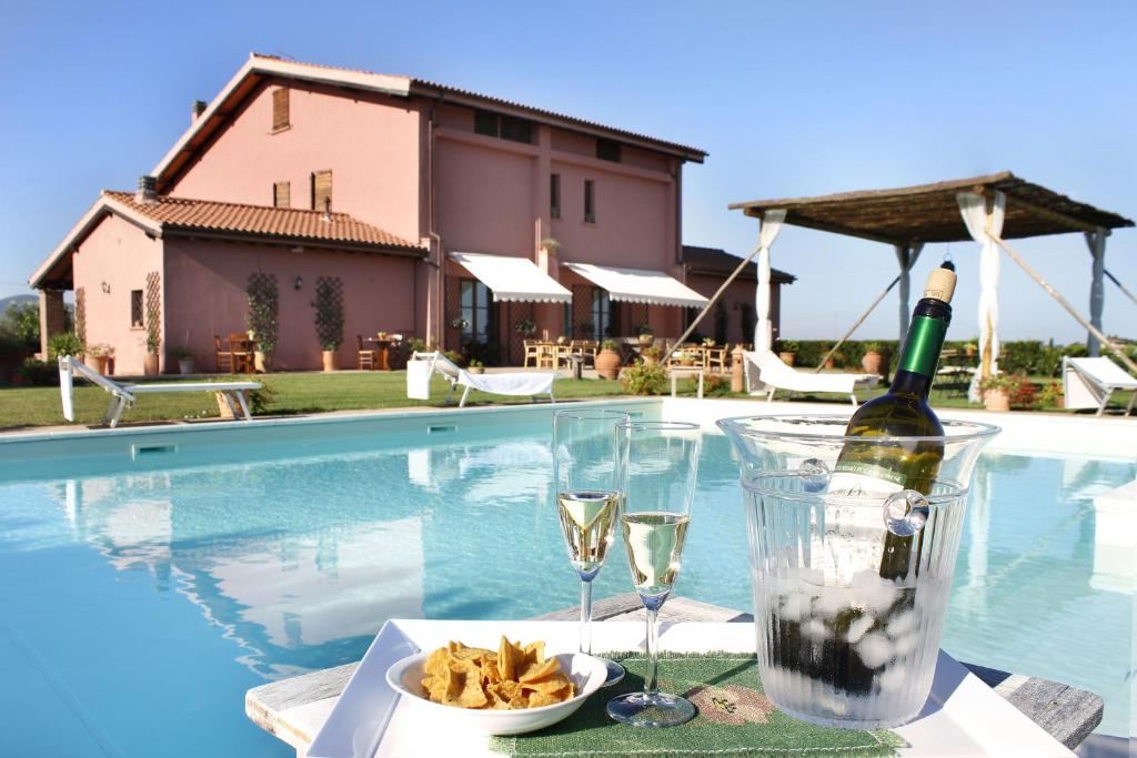 里斯佩施雅宝德乐西利奈农场酒店的游泳池旁的桌子,上面有一瓶葡萄酒和玻璃杯