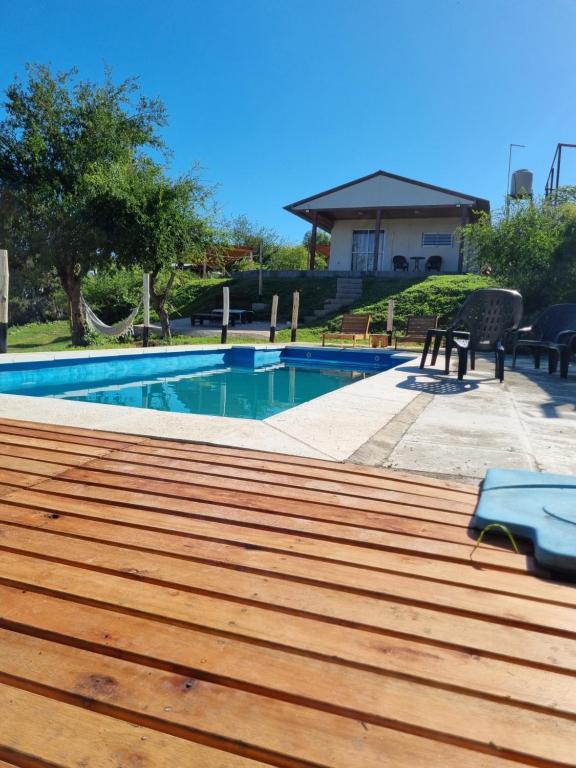 维拉卡洛斯帕兹Terrazas de Estancia的一座带木甲板的游泳池,位于一座房子旁边
