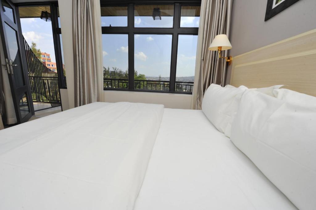 基加利荣耀酒店的卧室设有一张白色大床和一扇窗户。