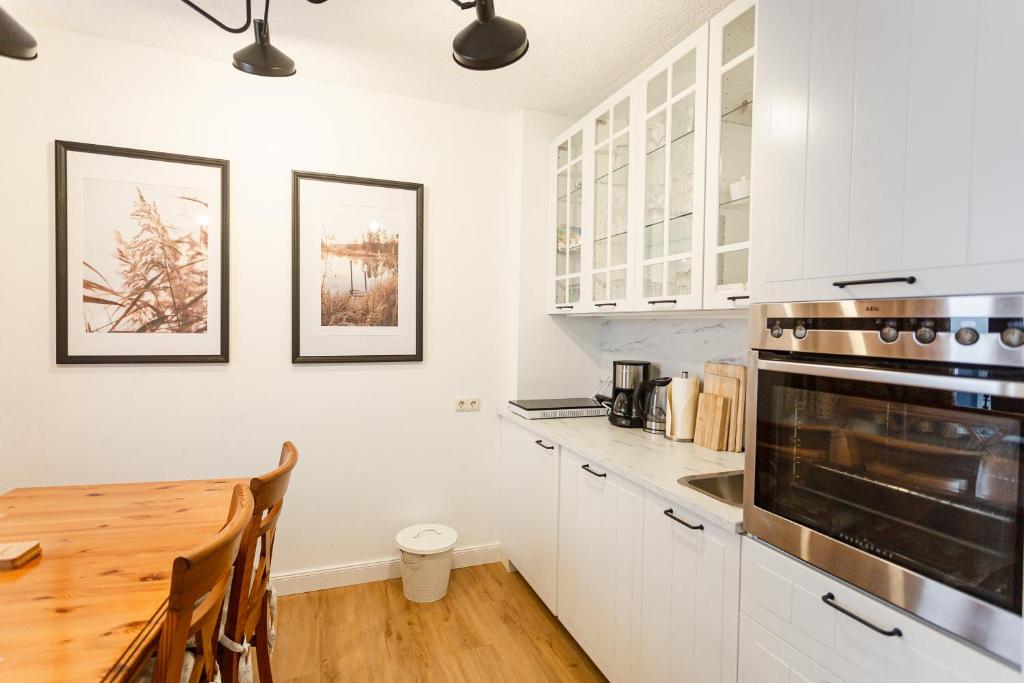 科赫姆NickHaus的厨房配有白色橱柜和木桌