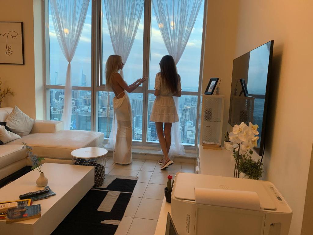 迪拜Torch 77的两个女人站在一个客厅,窗外望着