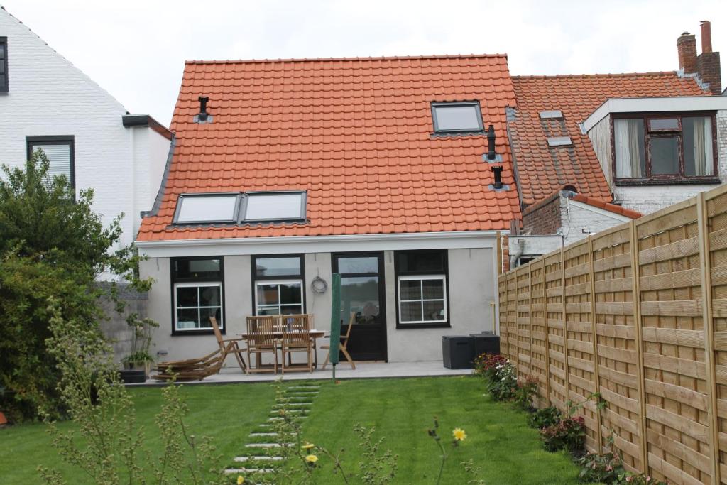 尼乌弗利特Huisje Zeertevree的一座带橙色屋顶和庭院的房子