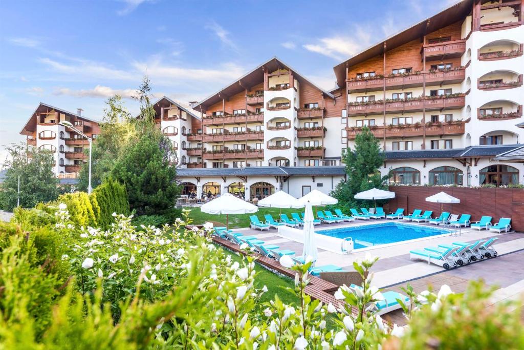 班斯科Kempinski Hotel Grand Arena Bansko的一座带游泳池和椅子的酒店和一座建筑