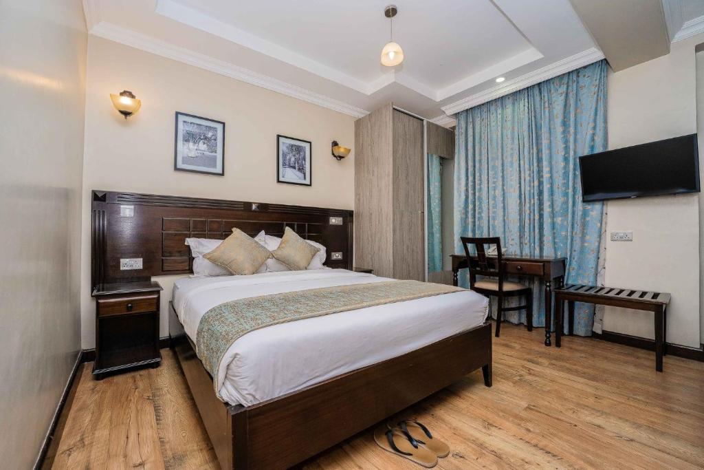 内罗毕Hemak Suites的一间卧室配有一张床、一张书桌和一台电视