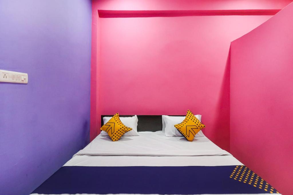 KākoriOYO 78880 Rajdhani Hotel的粉红色和紫色墙壁间的一张床