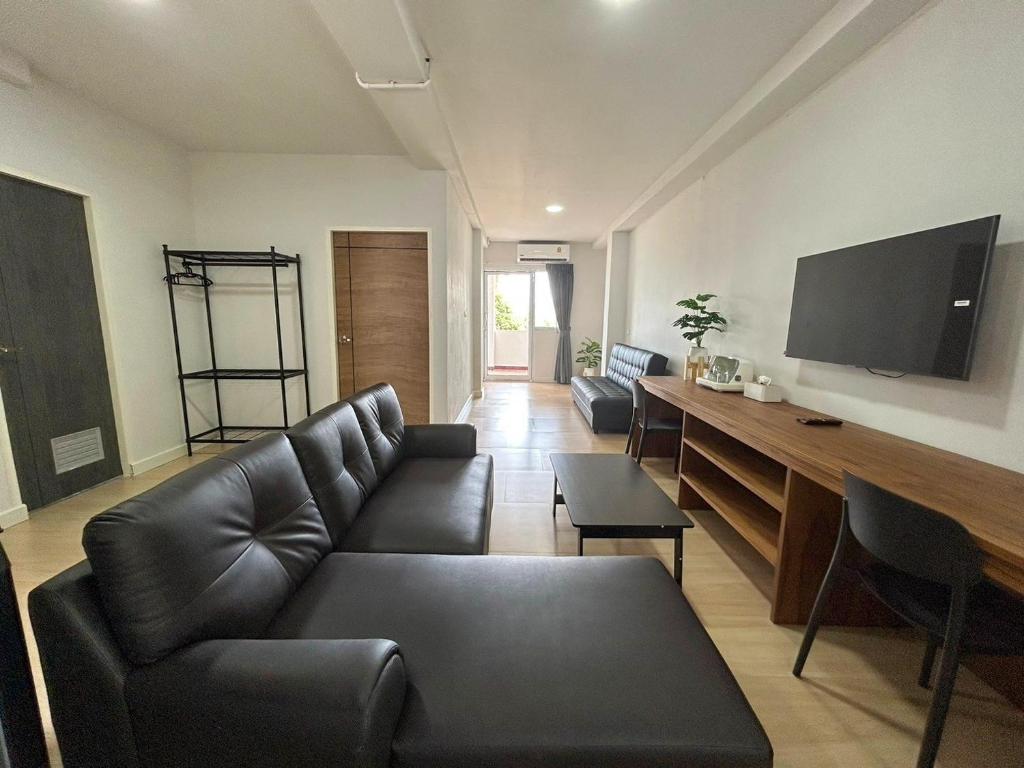 查汶idyllic apartment的客厅配有黑色沙发和平面电视。