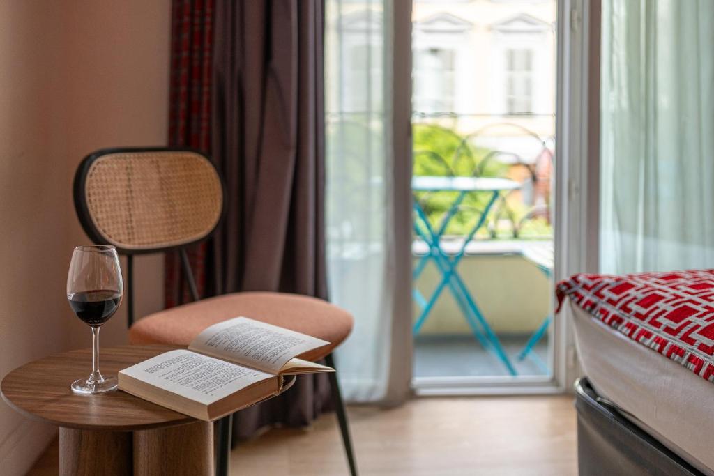 尼斯博雷阿酒店的一间卧室配有一杯葡萄酒和一把带书籍的椅子