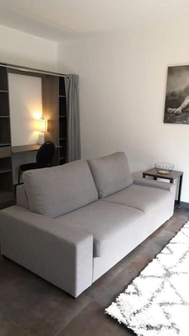 罗德兹Grand T1 très calme Proche centre ville Rodez的客厅配有一张白色沙发,配有一张桌子