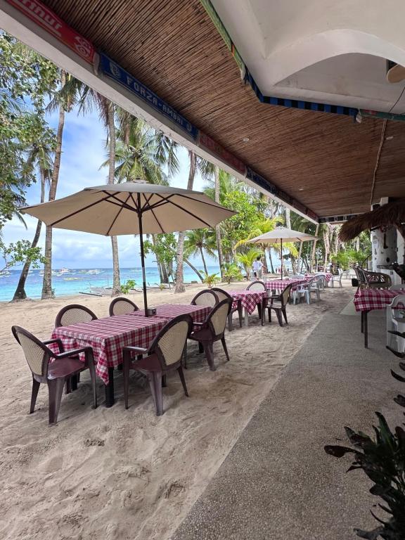 长滩岛Sundown Resort & Austrian Pension House的海滩上一组桌椅和遮阳伞